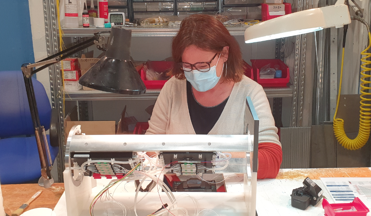 Evelyne Garçon en train de souder des fibres optiques, dans la galerie d’assemblage du CPPM